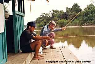 Close-up of Rick Seavey and Adriana Arevalo fishing off raft at Madre Selva Biological Station, Peru.